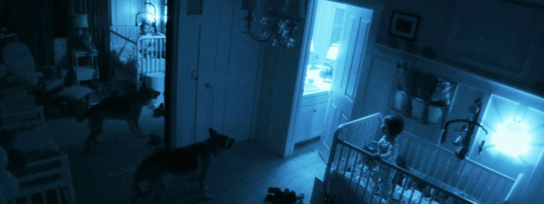 Blue tinted security camera footage of a baby in a cot inside the family home in Paranormal Activity 2 (2010).
